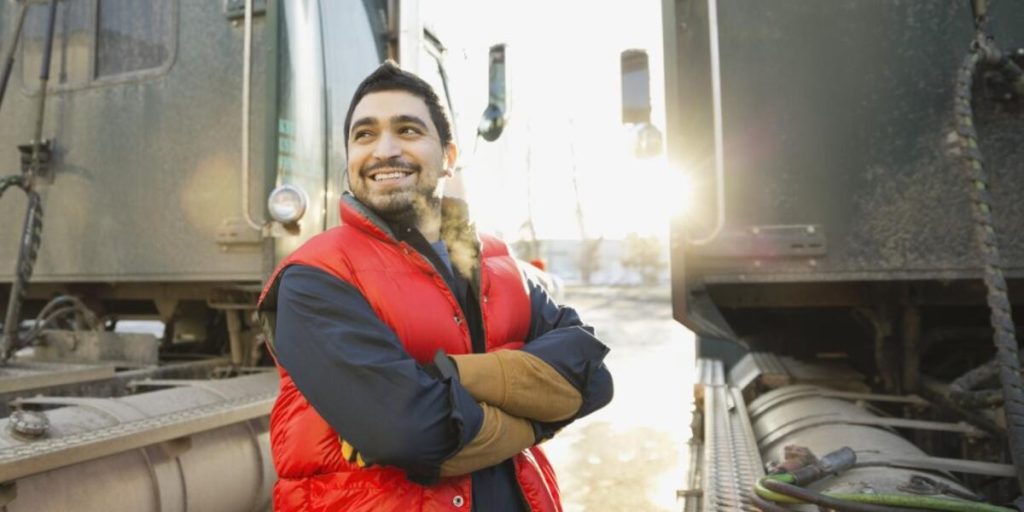 Confident worker standing by semi-trucks outdoors